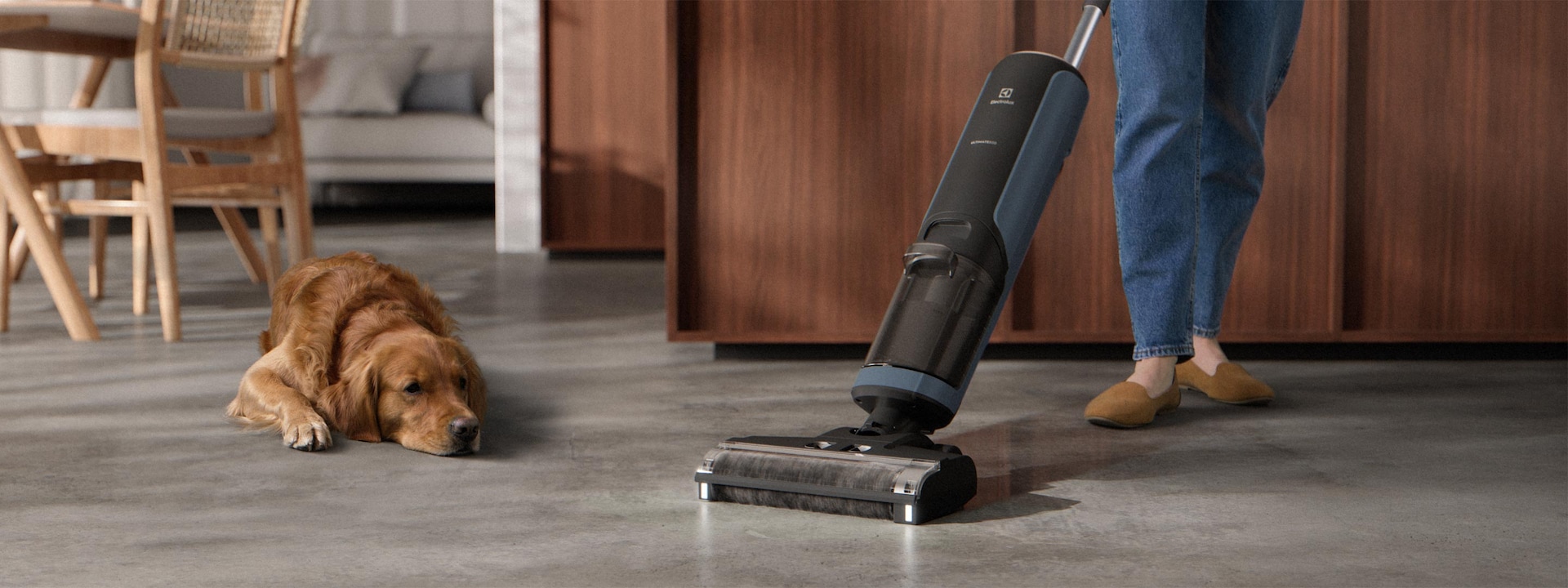 Žmogus plauna virtuvės grindis šalia gulinčio šuns